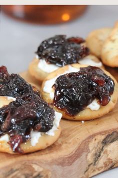 small pastries with jam on them sit on a wooden cutting board