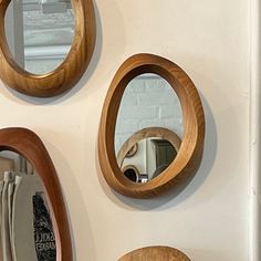 three circular mirrors mounted to the side of a wall next to a mirror on a shelf