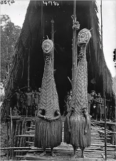 an old black and white photo of two people standing next to each other holding large objects