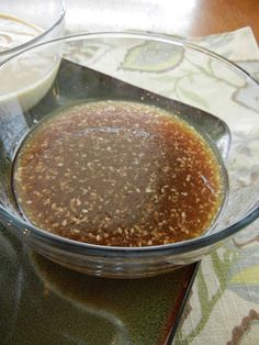 a glass bowl filled with brown liquid on top of a table next to a spoon