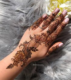 a woman's hand with hennap on it and flowers in the background