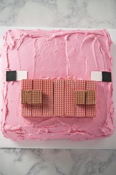 a cake with pink icing and some brown squares on the top is made to look like legos