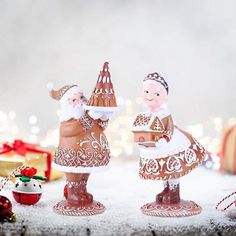 two little figurines are standing next to each other near christmas decorations and gifts