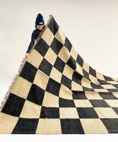 a man standing on top of a black and white checkered blanket