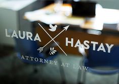 a glass sign that says, lauren hastay at the law office table with blue chairs