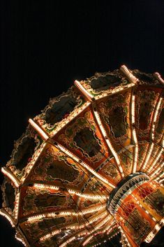 an illuminated carnival ride at night with lights on it's top and bottom half