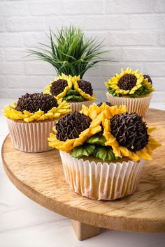 cupcakes decorated with sunflowers and chocolate frosting on a wooden platter