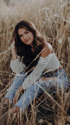 a woman is sitting in the tall grass