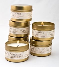 five candles with labels on them sitting next to each other in front of a white background