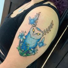 a woman's shoulder with an owl and flowers tattoo on her left upper arm