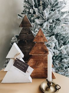 a small wooden christmas tree sitting on top of a table next to a lit candle