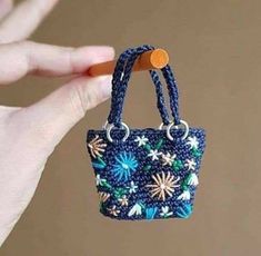 a hand holding a small blue purse with flowers on it