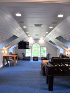 a room that has some couches and tables in it with lights on the ceiling