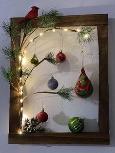 a wooden frame with ornaments hanging from it's sides and a bird perched on the branch