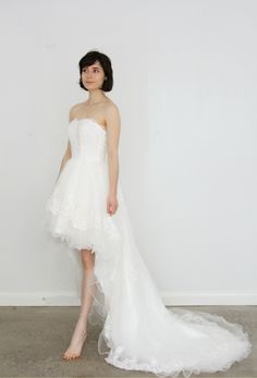 a woman in a white wedding dress standing against a wall