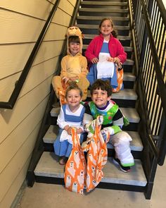 four children are sitting on the stairs wearing costumes