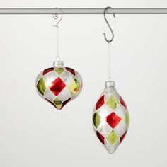 two glass ornaments hanging from a metal bar with hooks on it's sides, one is red and the other is green