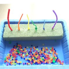 a blue tray filled with lots of different colored beads and plastic straws on top of it