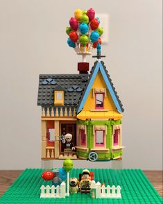 a lego house with balloons on the roof and a toy car parked in front of it