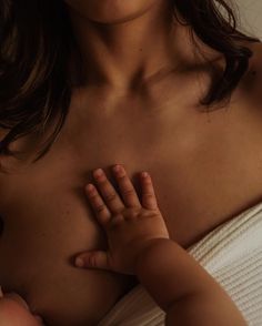 a close up of a woman holding a baby's breast with her hands on her chest