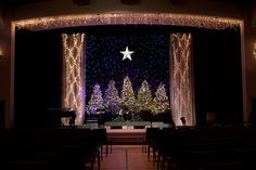 an empty church with christmas decorations and lights on the stage, as seen from across the room