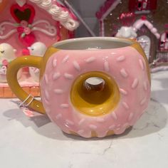 a pink donut shaped coffee mug sitting on top of a table next to a house