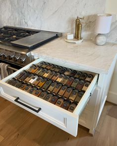 an open drawer on the side of a stove in a kitchen with marble counter tops