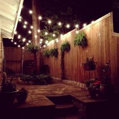 an outdoor patio with potted plants and string lights