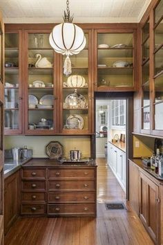 a kitchen with wooden floors and lots of cupboards filled with dishes on top of them