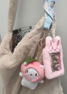 a stuffed animal is holding onto a cell phone case with a keychain attached to it