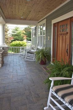 a screen shot of a porch with rocking chairs and potted plants on the side