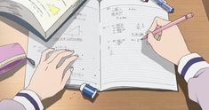 someone is writing on a book with pencils and eraser next to it, while another person holds a pen in their hand