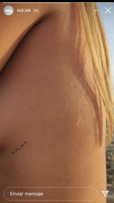 the back of a woman's shoulder with small tattoos on it and an arrow in the middle