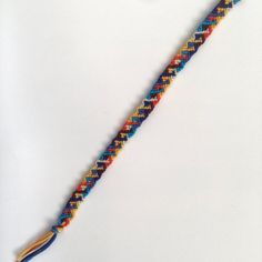 a multicolored bracelet with a tassel on the end and a gold clasp