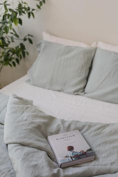 a book is laying on top of a bed with white sheets and pillowcases