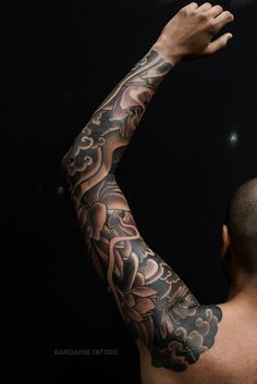 a man with tattoos on his arm and arms is holding something up in the air