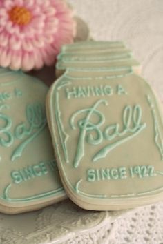 two decorated cookies sitting on top of a table next to a pink flower in a vase