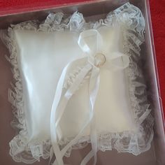 a white ring pillow in a box on a red surface