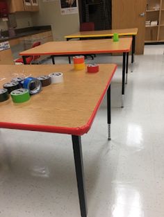 a classroom with several tables and chairs in the middle, one has empty cups on it