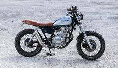 a blue and white motorcycle parked on top of a dirt field