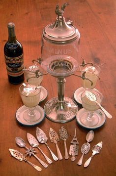 an assortment of silverware on a wooden table with bottles and spoons next to it