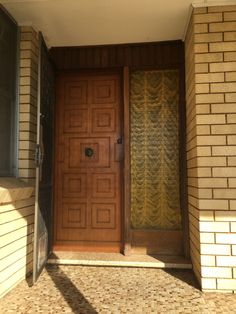 a wooden door sitting inside of a brick wall next to a window on top of a tiled floor