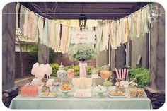 a table covered in lots of food under a tent with bunting and streamers