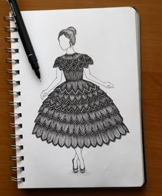 a drawing of a woman in a dress on a notepad next to a pen