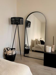 a large mirror sitting next to a black basket on top of a wooden floor in a room