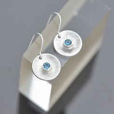 Handmade Topaz earrings - Round sterling silver and blue Topaz earrings, concave domed with textured interior and subtle radial lines bring emphasis to the stones.  * Gemstone earrings - Faceted London Blue Topaz, 4mm in diameter  * December birthstone, December earrings * Sterling silver diameter 14mm * Gift for her - Boxed, ready for gifting Handmade to order - You'll receive your own pair of Topaz earrings, like those shown in the photos. We have one available for immediate dispatch Follows u Modern Silver Birthstone Earrings, Modern Silver Earrings With Birthstone, December Birthstone Jewelry, Sterling Silver Heart Necklace, Peridot Pendant, Aquamarine Pendant, Topaz Jewelry, Jewellery Gifts, Birthstone Earrings