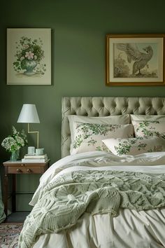 a bedroom with green walls and white bedding, two framed pictures on the wall