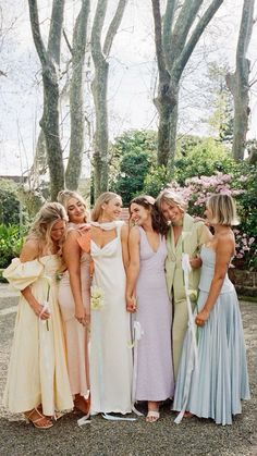 a group of women standing next to each other wearing dresses and holding bouquets in their hands