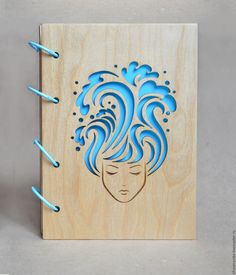 a wooden notebook with an image of a woman's face on it and blue spirals