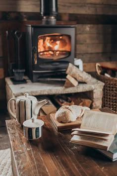 an open book sitting on top of a wooden table next to a wood burning stove